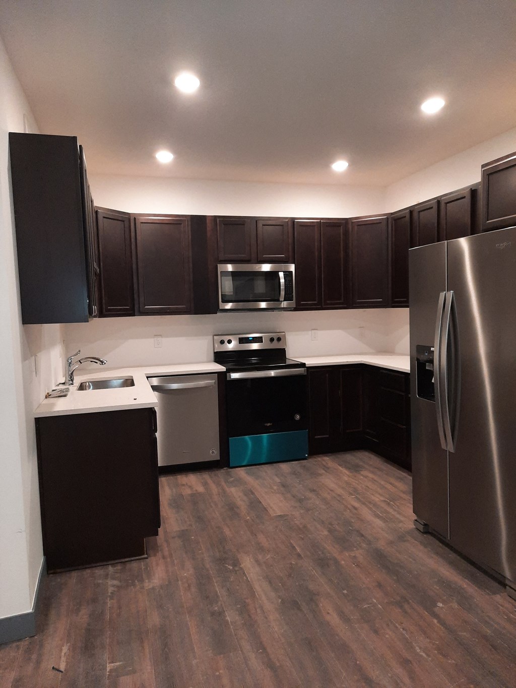 an empty kitchen with stainless steel appliances and dark wood cabinets