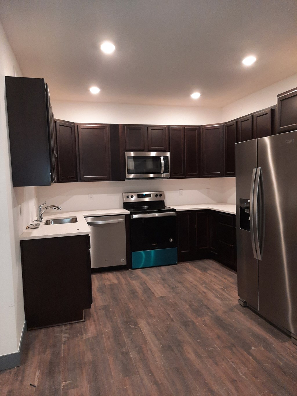 an empty kitchen with stainless steel appliances and dark cabinets