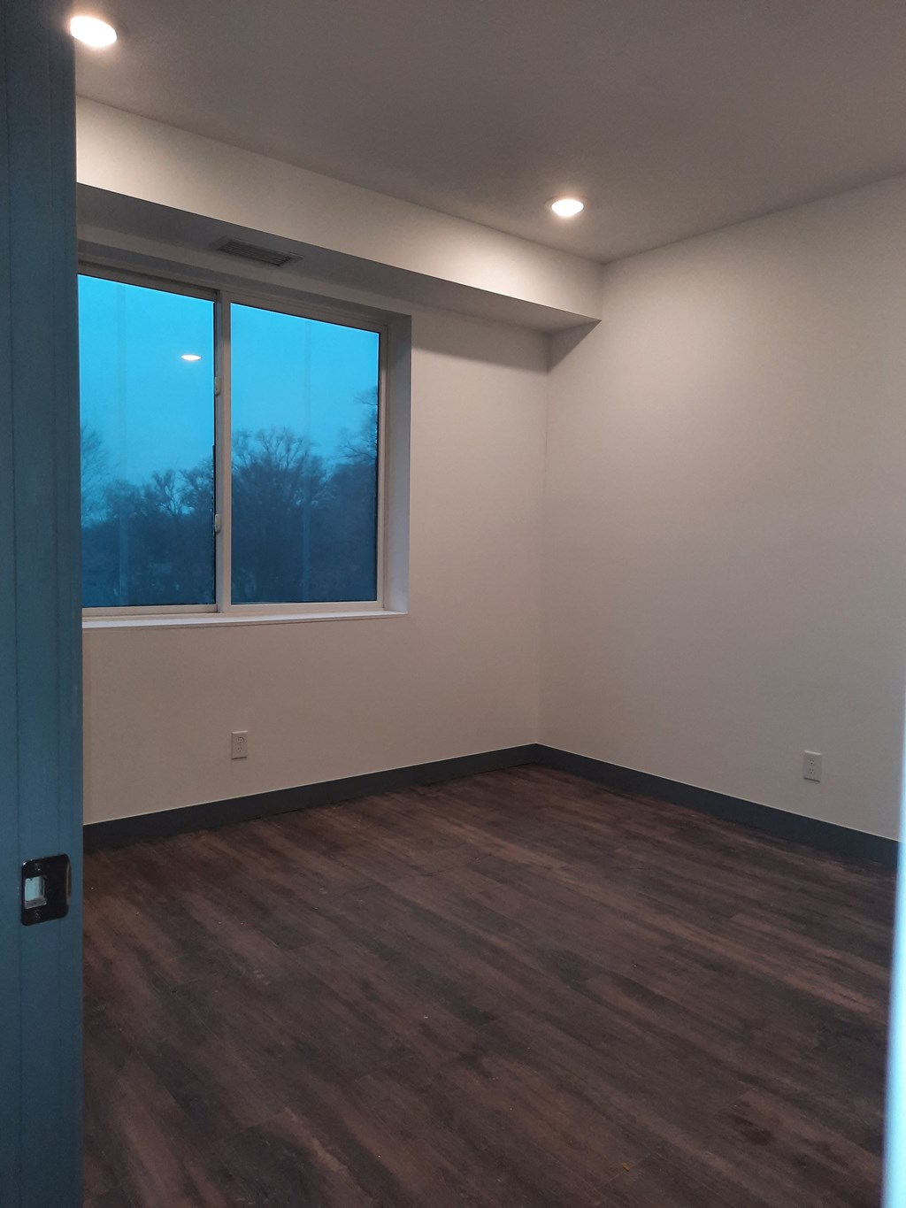 an empty room with wooden floors and a window