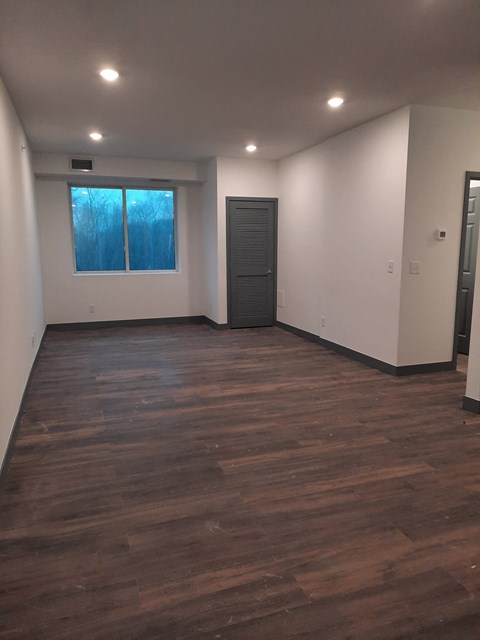 an empty living room with a door and a window