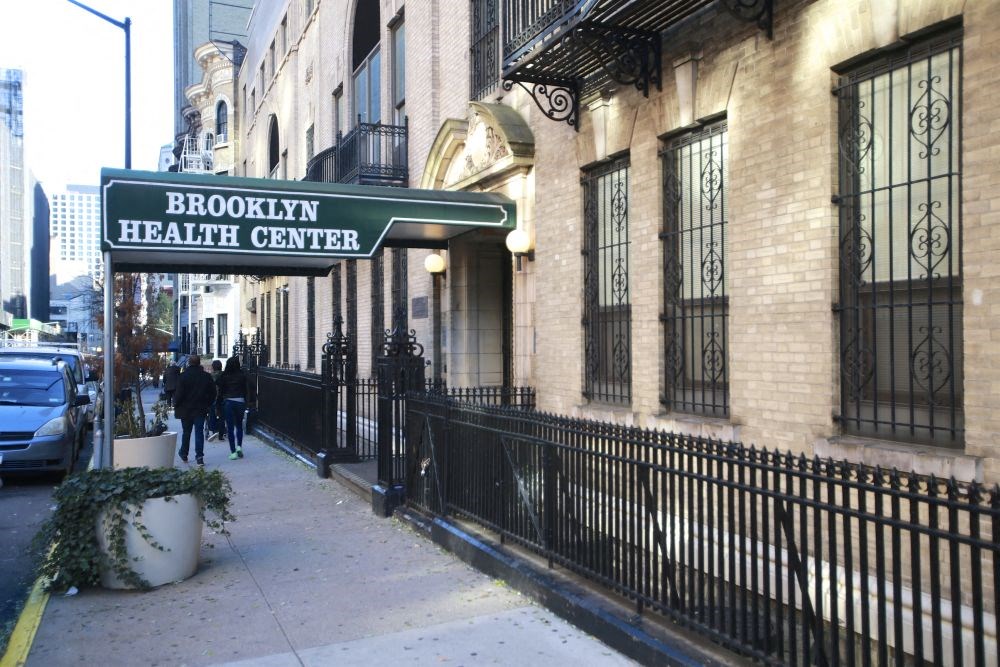 a couple of people walking down a sidewalk in front of a building