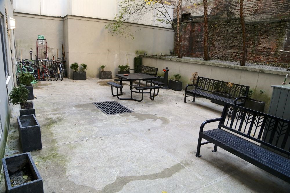 a courtyard with benches and tables and a brick wall