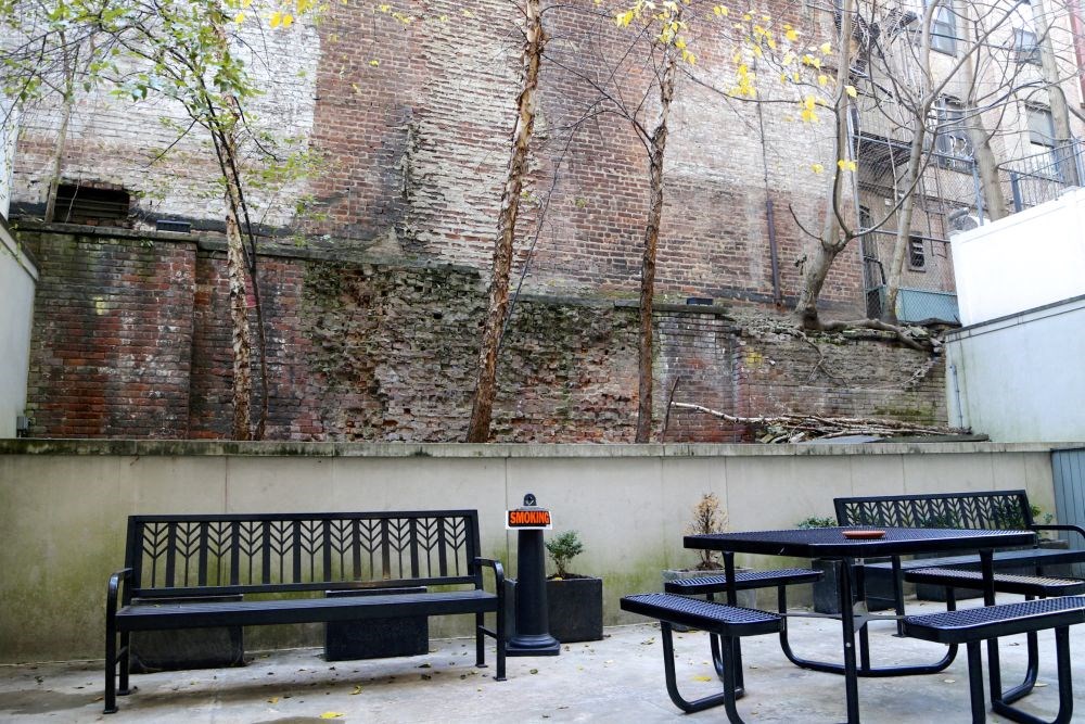 a group of benches and tables in front of a brick wall