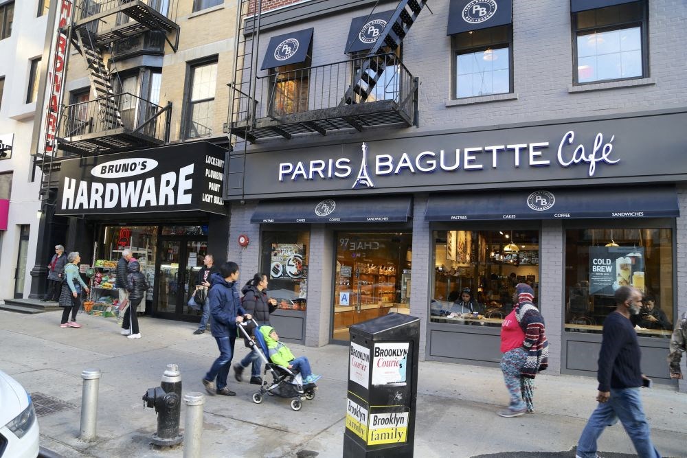 people walking on a city street in front of a coffee shop