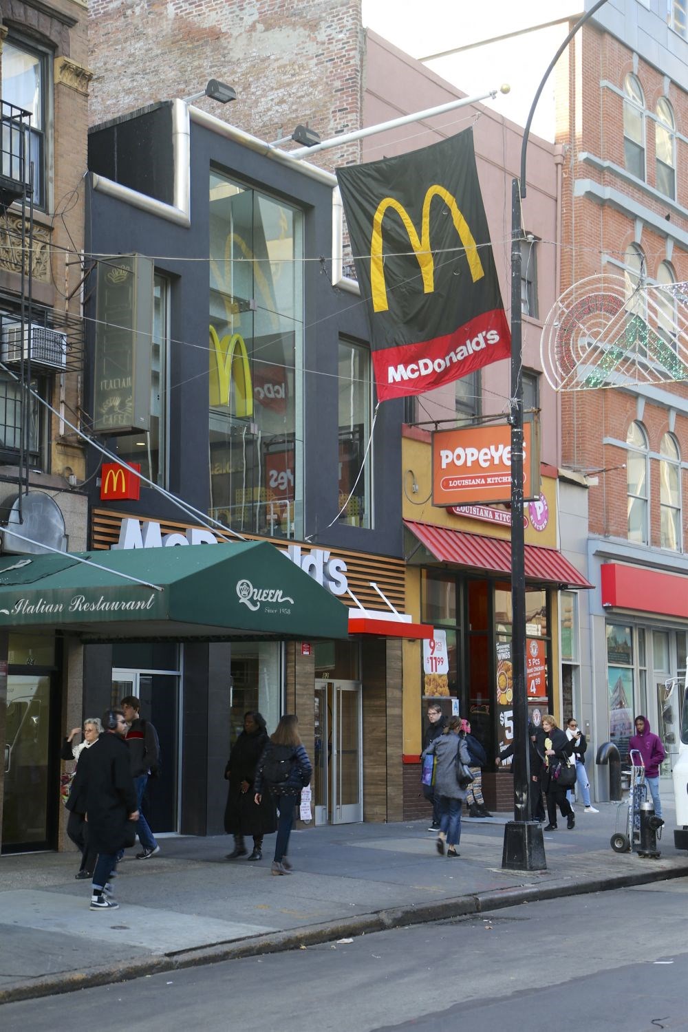 people walking down a street in front of a mcdonalds restaurant