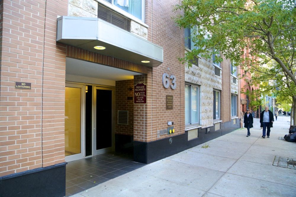 a brick building with two people walking down a sidewalk