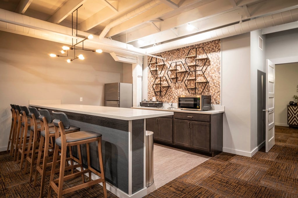 a kitchen with a counter and chairs and a refrigerator