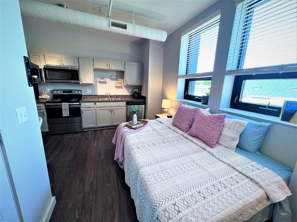 a small living room with a bed and a kitchen