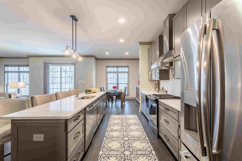 a large kitchen with stainless steel appliances and white counter tops