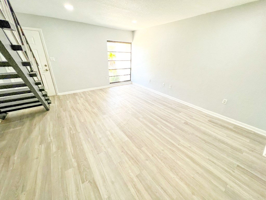 an empty living room with hardwood floors and a staircase