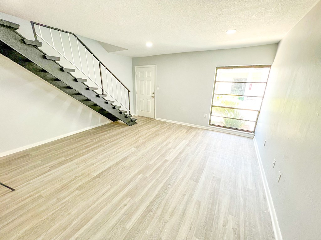 an empty living room with wood flooring and a staircase