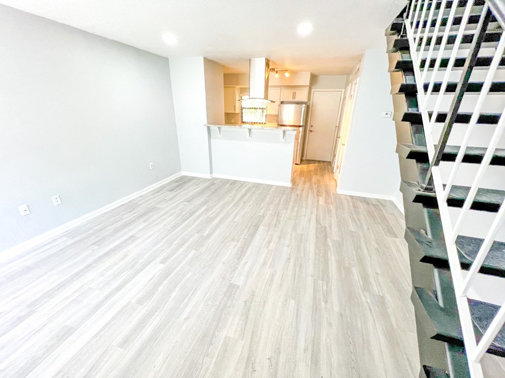 an empty living room with a staircase and a wood floor