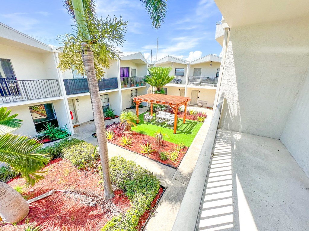 a courtyard with palm trees and a table in the middle