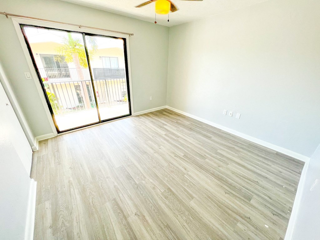 an empty living room with wood floors and a sliding glass door
