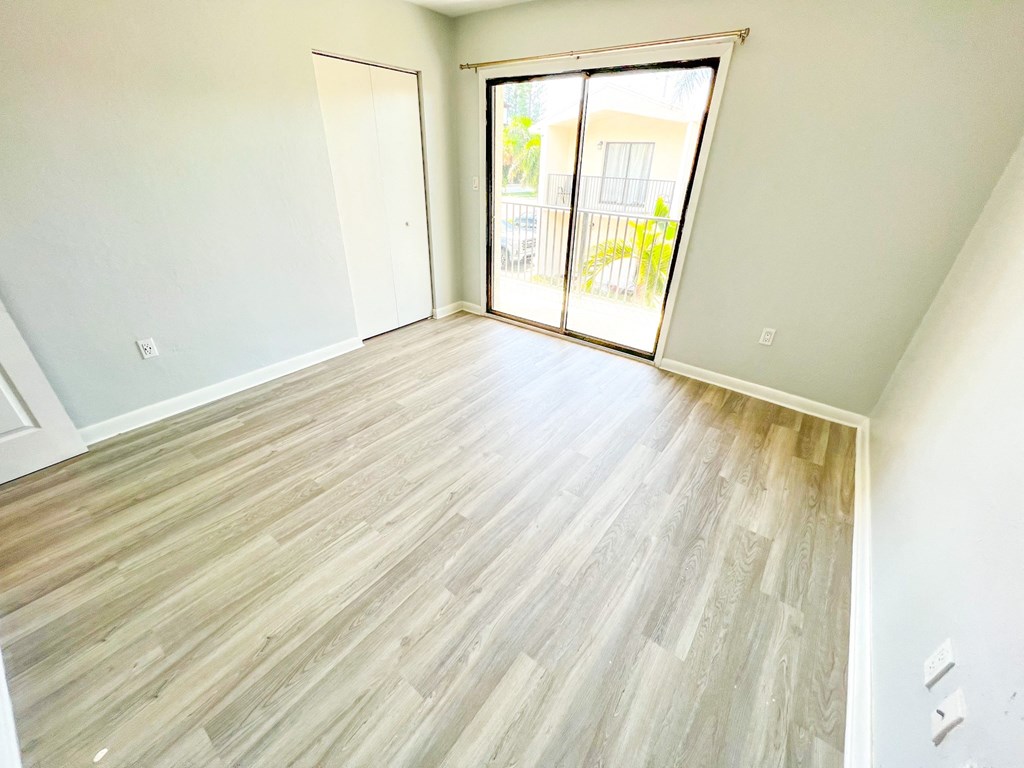 an empty living room with wood flooring and a sliding glass door