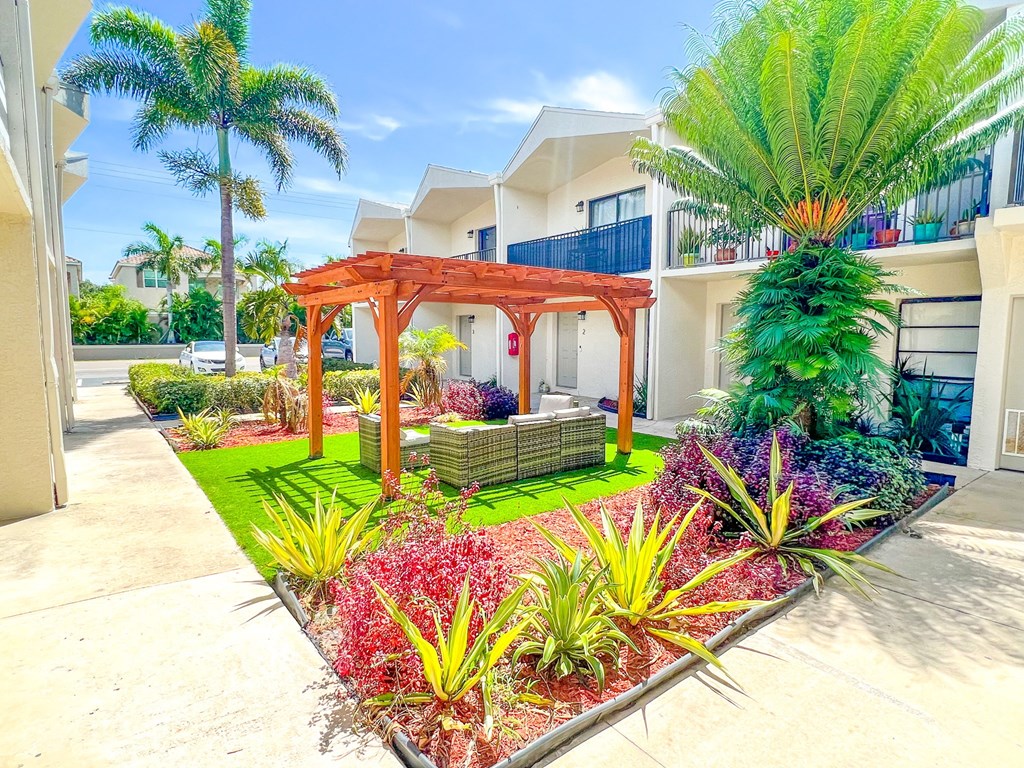 a landscaped yard with a gazebo and palm trees