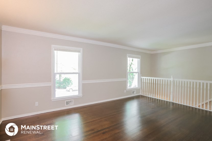 an empty room with a wood floor and a white railing and two windows