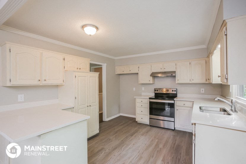 a kitchen with white cabinets and white counter tops and a black stove top oven