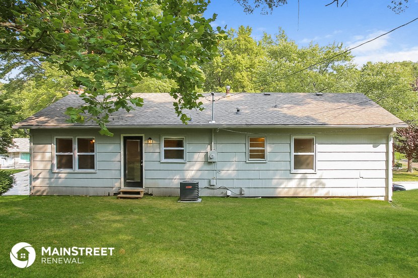 a light blue house with a yard and a tree