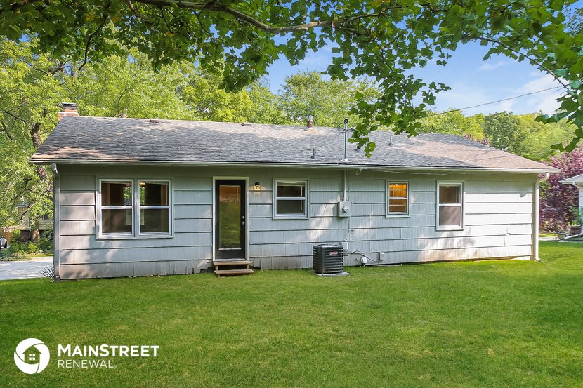 a blue and white house with a yard and trees