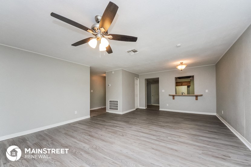 the spacious living room with ceiling fan and wood flooring