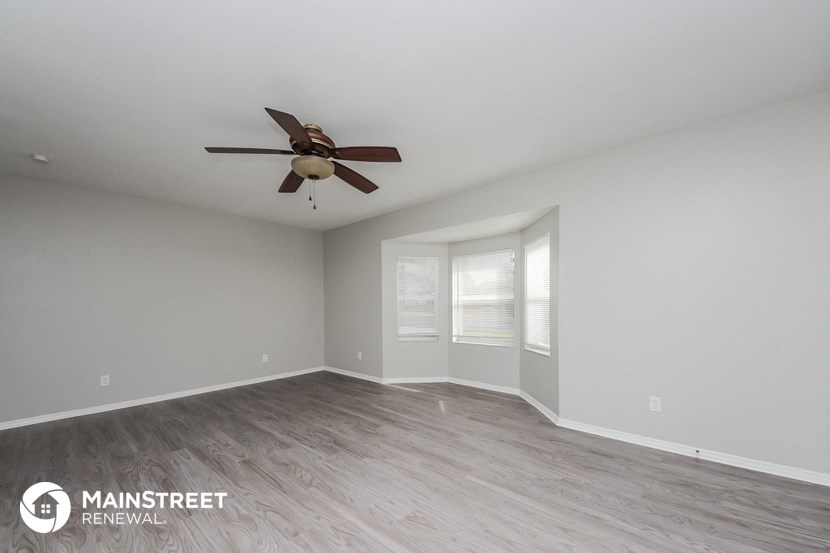 the spacious living room with ceiling fan and wood flooring
