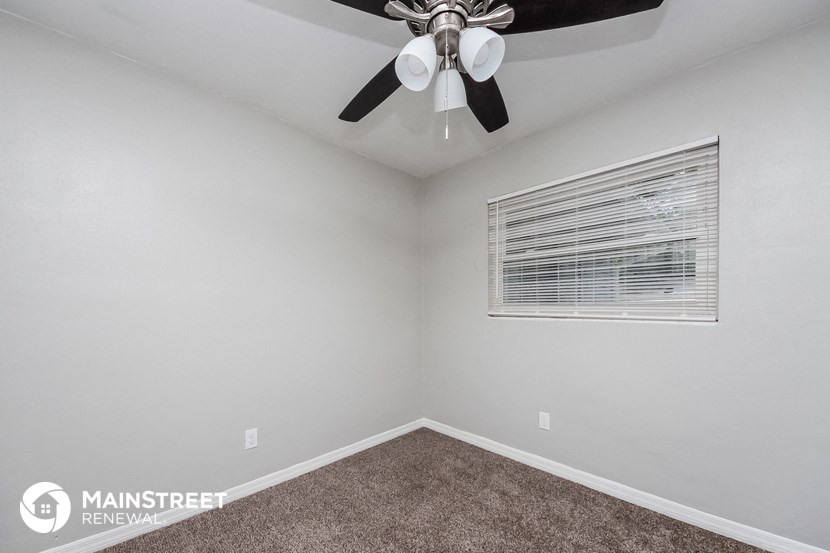 the bedroom has a ceiling fan and a window