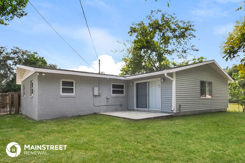 a small gray house with a yard and a garage