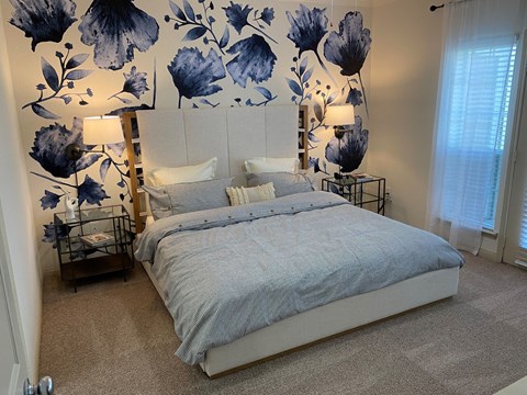 a bedroom with a bed and a blue and white floral wall paper