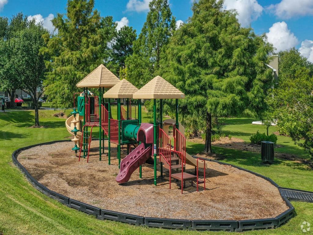 a playground with a slide and chairs in a park