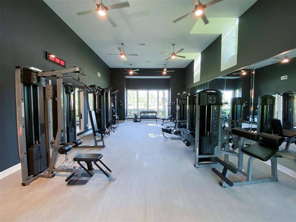a gym with weights and cardio equipment on the floor and a window
