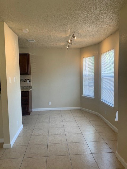 an empty living room with three windows and a tile floor