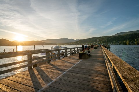 people walking on a dock on the water at sunset