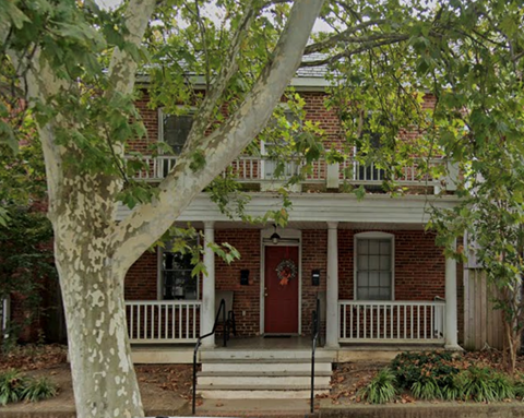 A red door is on the front of a brick house.