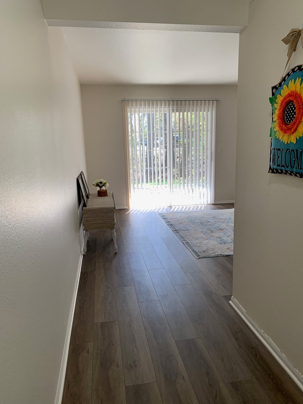 a living room and hallway with wood flooring and a window