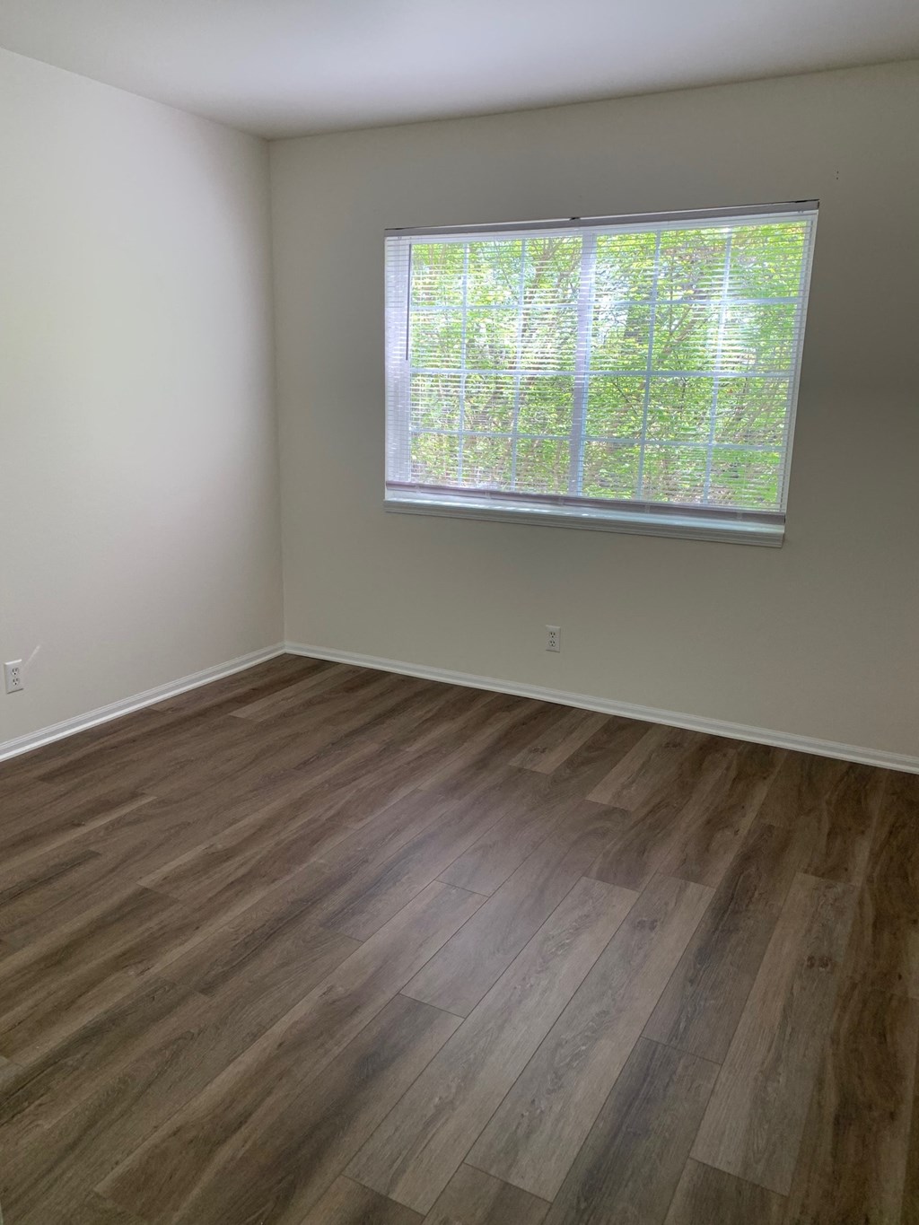 an empty room with wooden floors and a window