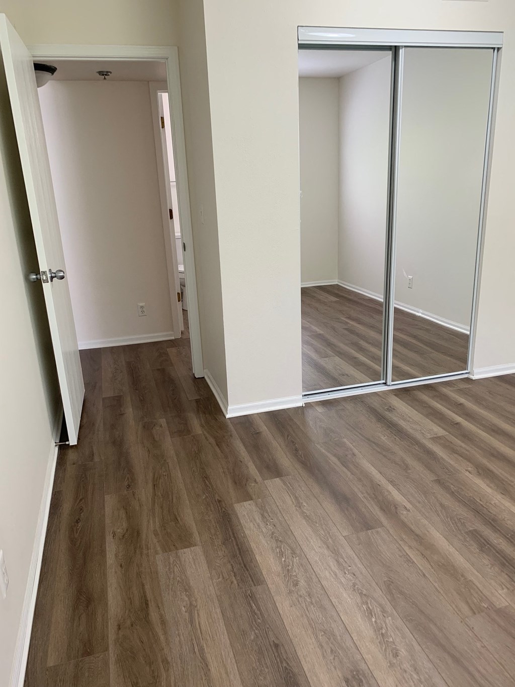 a room with wood flooring and a mirrored closet