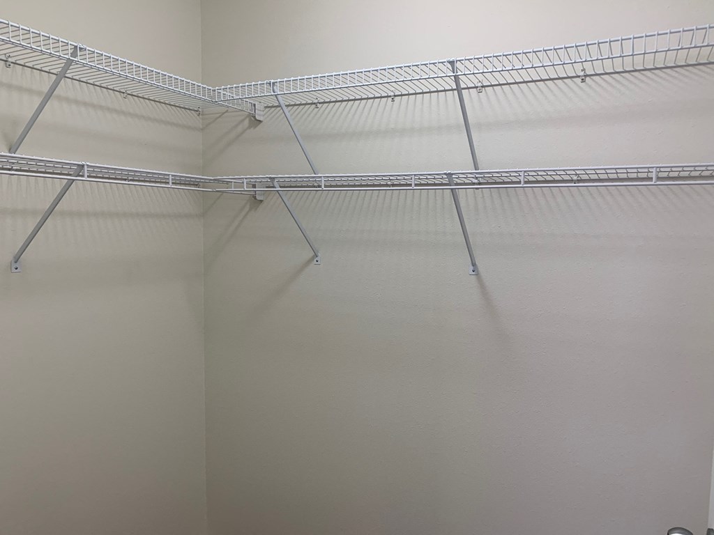 a walk in closet with a wire rack on the ceiling