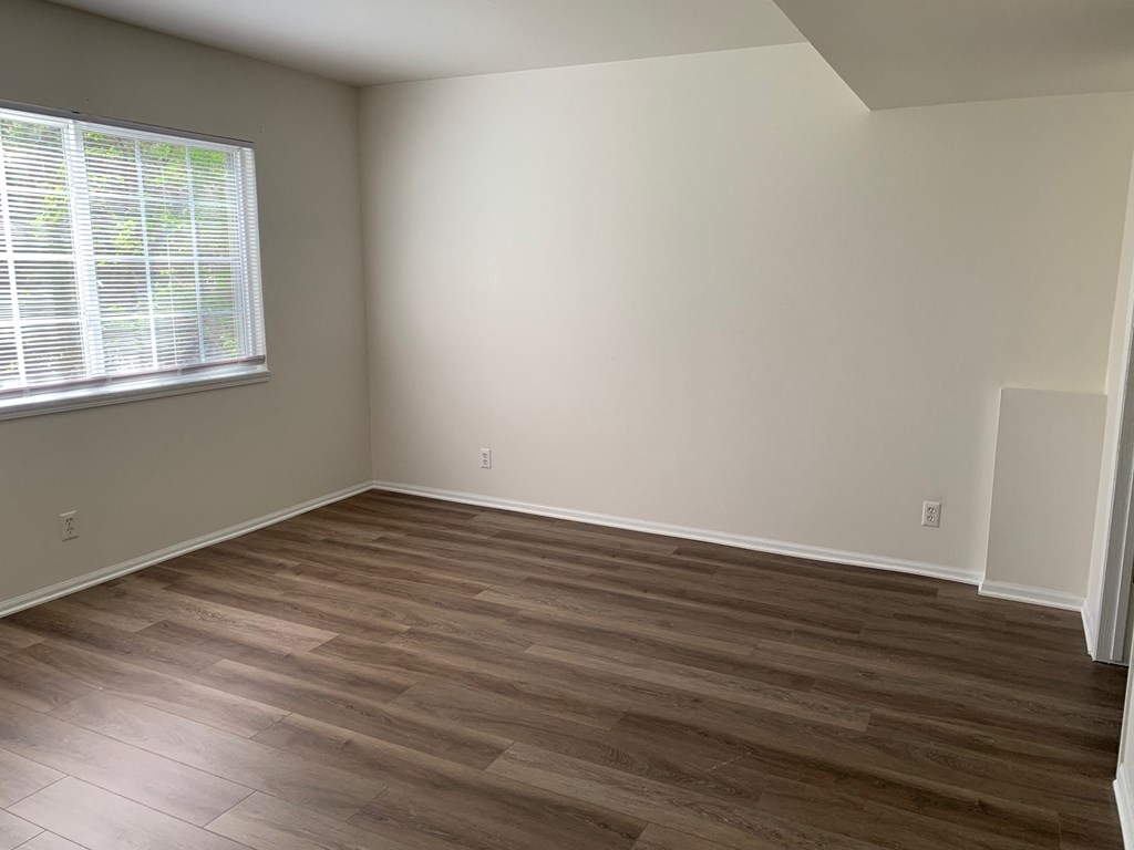an empty room with wooden floors and a window