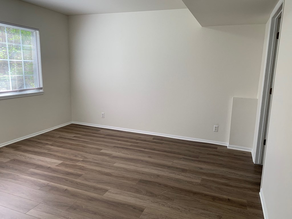 an empty room with wooden floors and a window