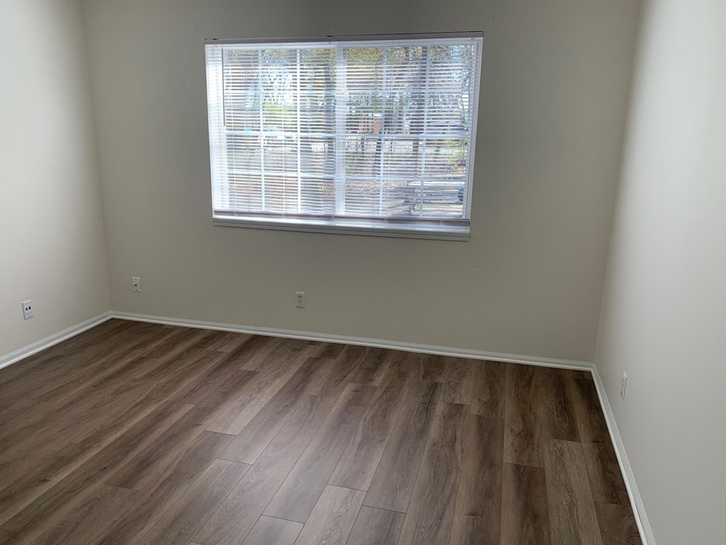 an empty room with wood floors and a window