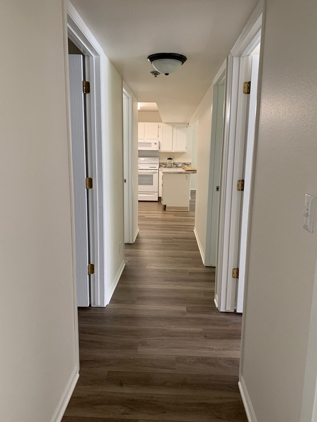 a view of a hallway with wood floors and a kitchen