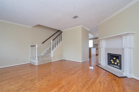 A living room with a fireplace and a staircase.