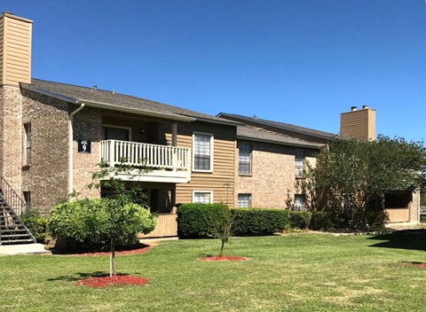 a brick apartment building with a balcony and a yard