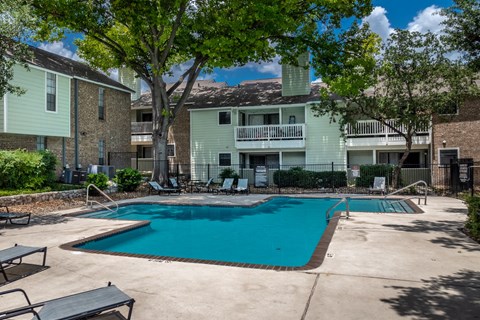 A swimming pool surrounded by lounge chairs and trees.
