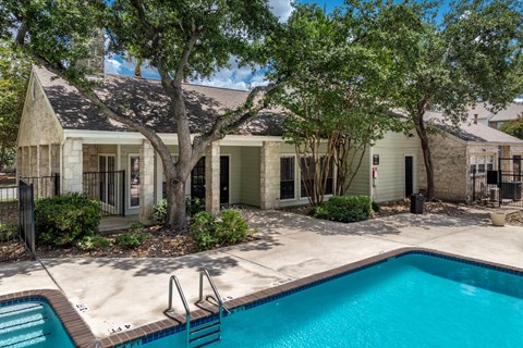 A pool surrounded by trees and a building.
