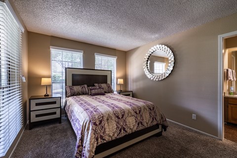 A bedroom with a bed, nightstands, and a mirror.