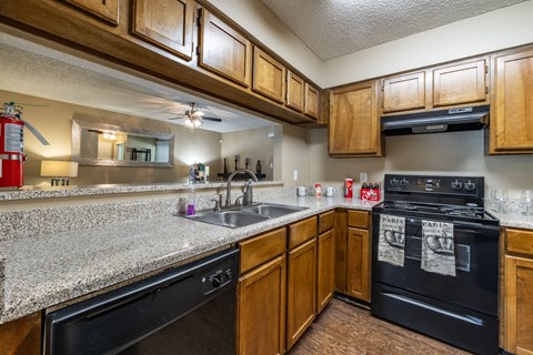 A kitchen with black appliances and wooden cabinets.