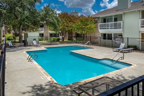 A swimming pool surrounded by a fence and trees.