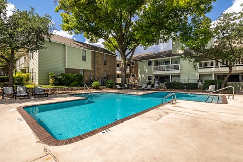 A swimming pool surrounded by a concrete patio and trees.